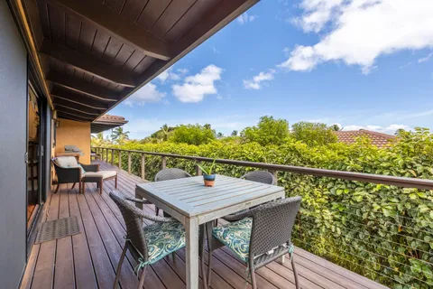 a balcony with wooden floor table and chairs