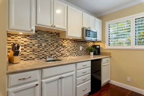a kitchen with granite countertop white cabinets and black stainless steel appliances