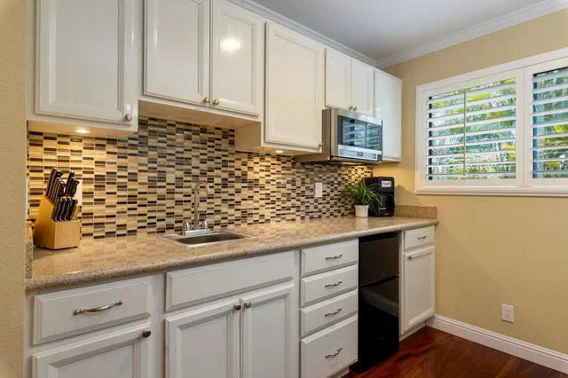 a kitchen with granite countertop white cabinets and black stainless steel appliances