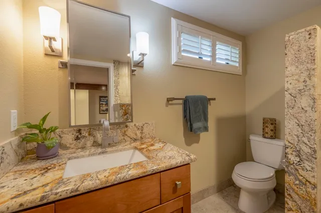 a bathroom with a granite countertop sink mirror vanity and toilet