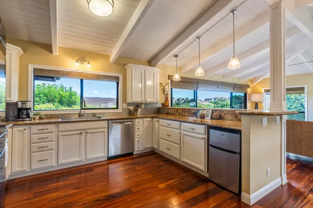 a kitchen with stainless steel appliances granite countertop wooden floors and white cabinets