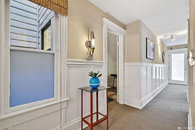 a view of a hallway to a livingroom with wooden floor and furniture