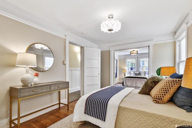 a bedroom with a bed a mirror on dresser and a chandelier