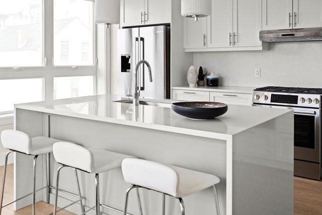 a kitchen with stainless steel appliances a table and chairs in it