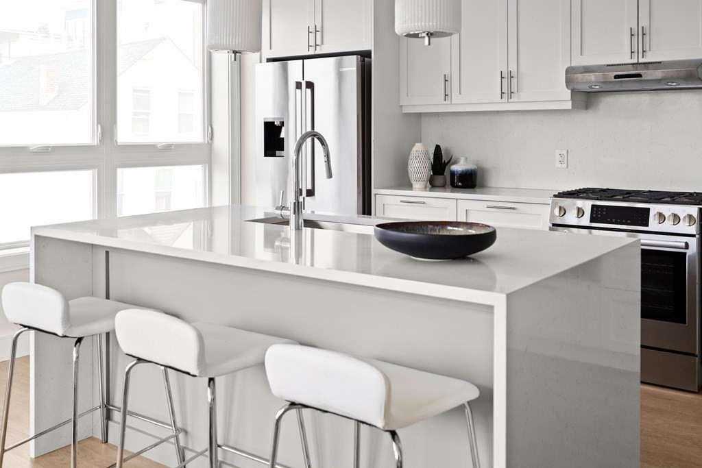 301 Border Street, Unit 311 Boston, MA 02128 - Photo 18 of 33 a kitchen with stainless steel appliances a table and chairs in it