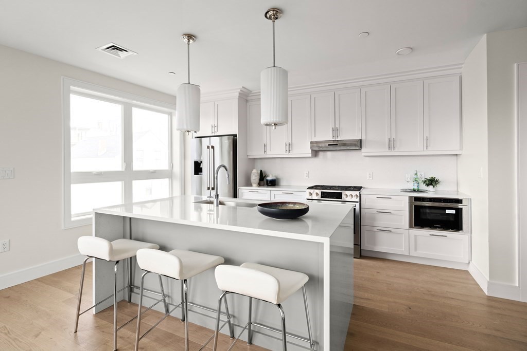 301 Border Street, Unit 311 Boston, MA 02128 - Photo 8 of 33 a kitchen with stainless steel appliances granite countertop a stove a sink a refrigerator and white cabinets with wooden floor