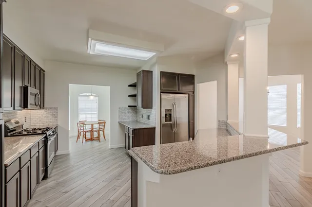 a kitchen with stainless steel appliances granite countertop a refrigerator a stove and a wooden floors