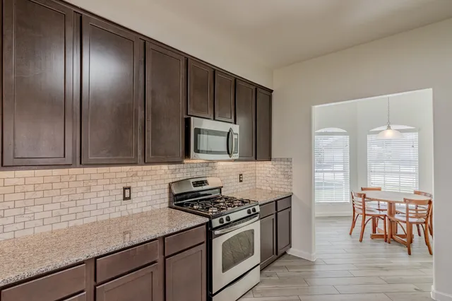 a kitchen with stainless steel appliances granite countertop a stove a sink and a microwave