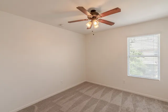 an empty room with a chandelier fan and closet