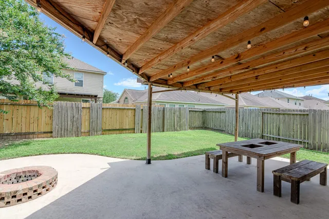 a view of a backyard with table and chairs under a large tree