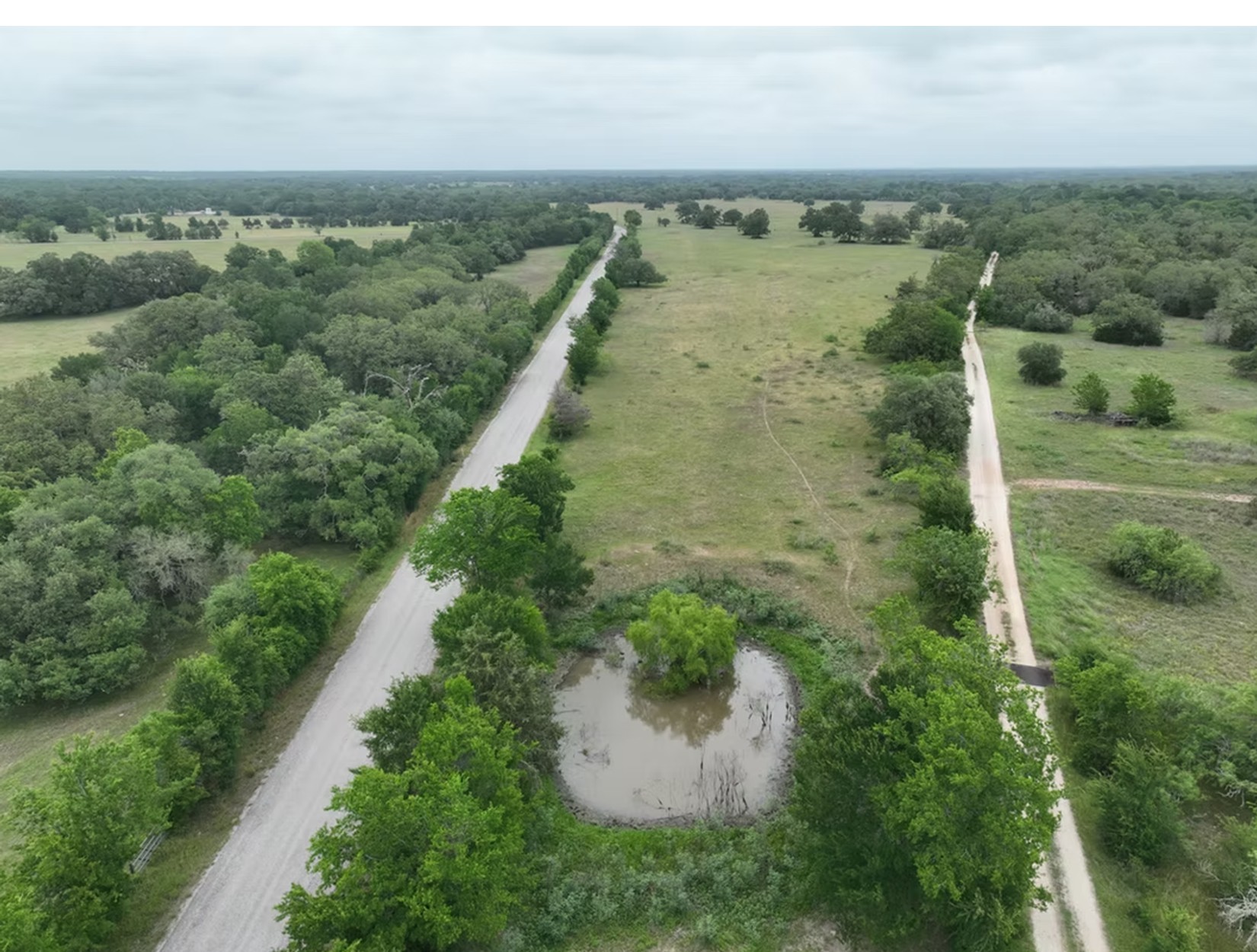 Lot 1-tbd Rd Ledbetter Tx 78946 Road Ledbetter, TX 78946 - Photo 1 of 4 An aerial perspective showcases a private pond nestled amidst vast green pastures and mature trees.