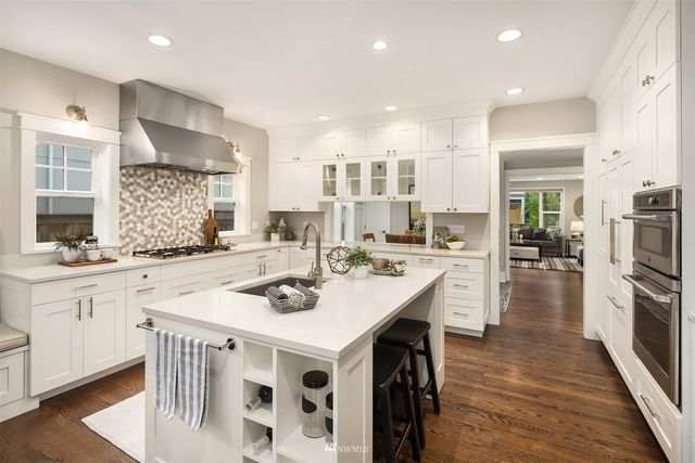 a kitchen with a sink stove and white cabinets with wooden floor