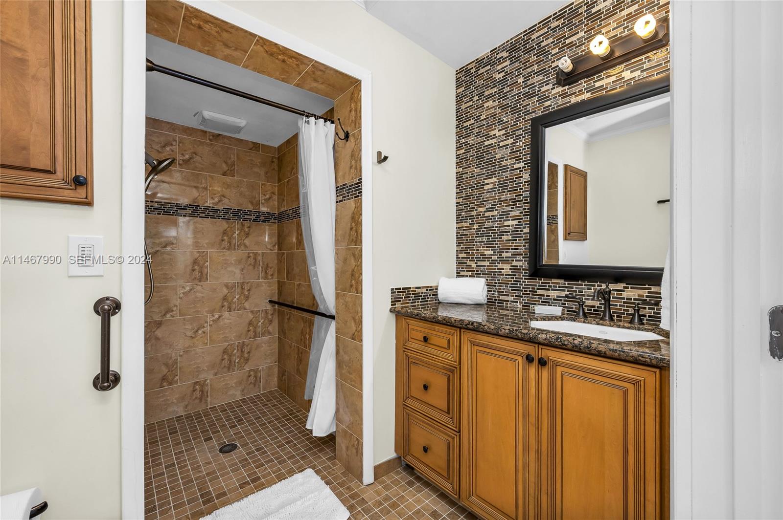 2500 Northeast 199th Street Miami, FL 33180 - Photo 41 of 72 a bathroom with a granite countertop sink a mirror and shower