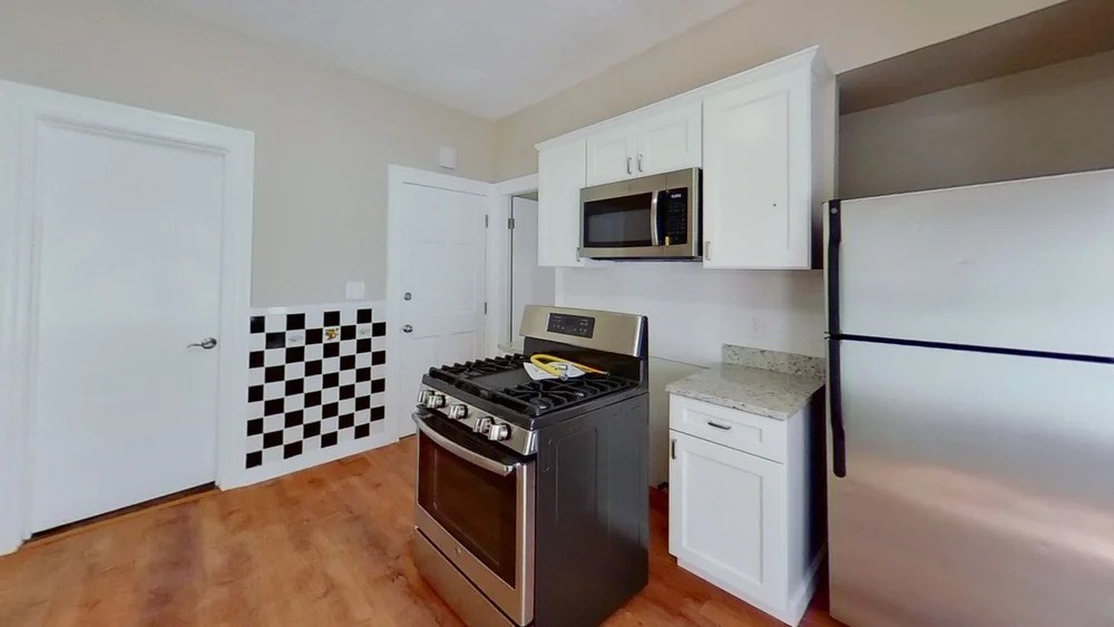 121 George Street, Unit 1 Boston, MA 02119 - Photo 2 of 7 a kitchen with granite countertop a stove and a microwave