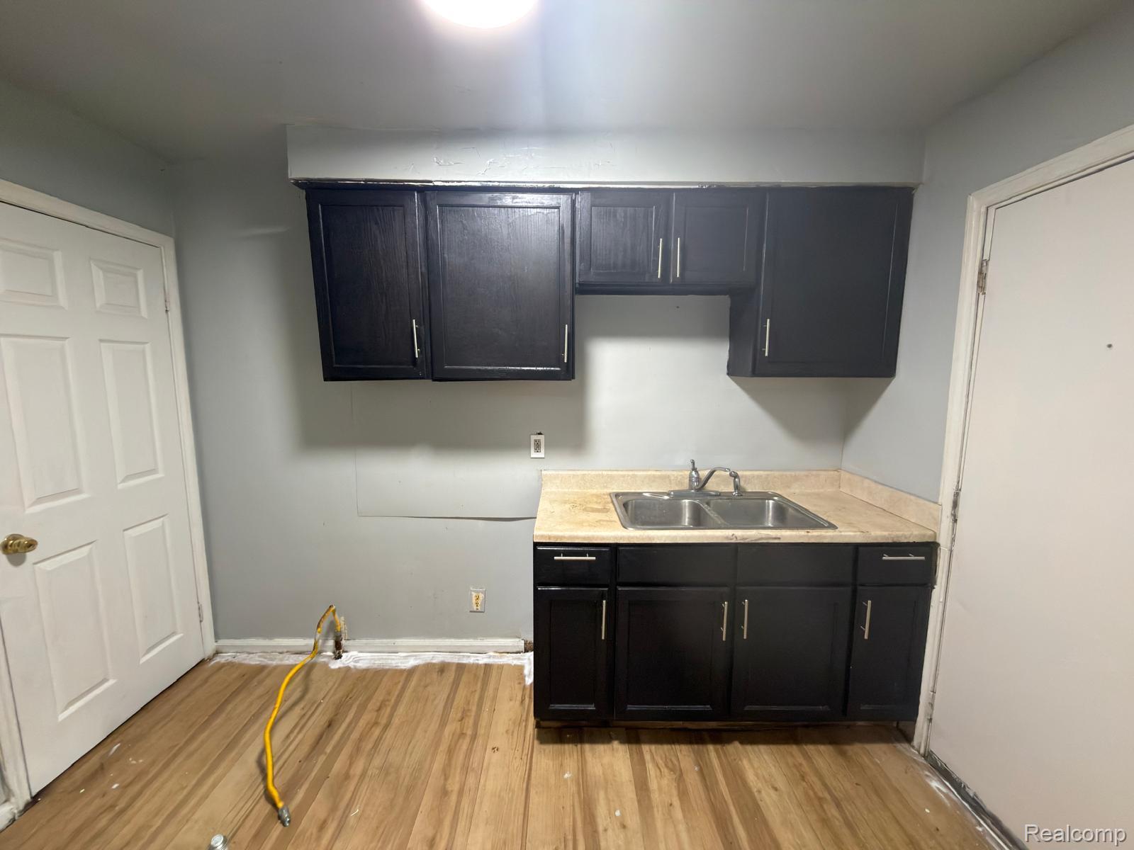 8837 Evergreen Road Detroit, MI 48228 - Photo 3 of 16 Kitchen space featuring wood-finish flooring, dark cabinetry, and a double basin stainless steel sink