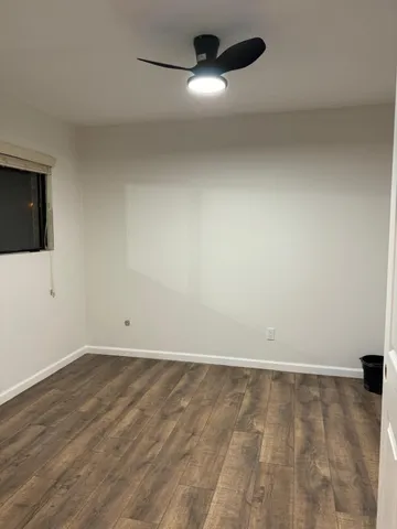 a view of an empty room with wooden floor and a window