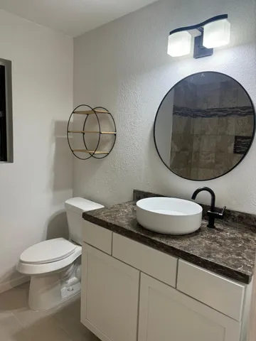 a bathroom with a granite countertop toilet sink and mirror