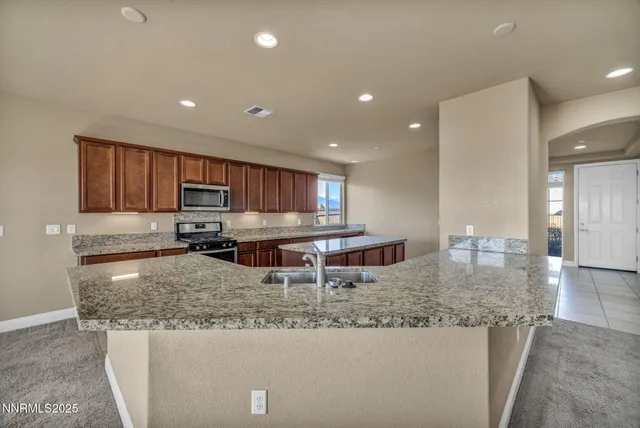 a kitchen with kitchen island granite countertop a stove and a sink