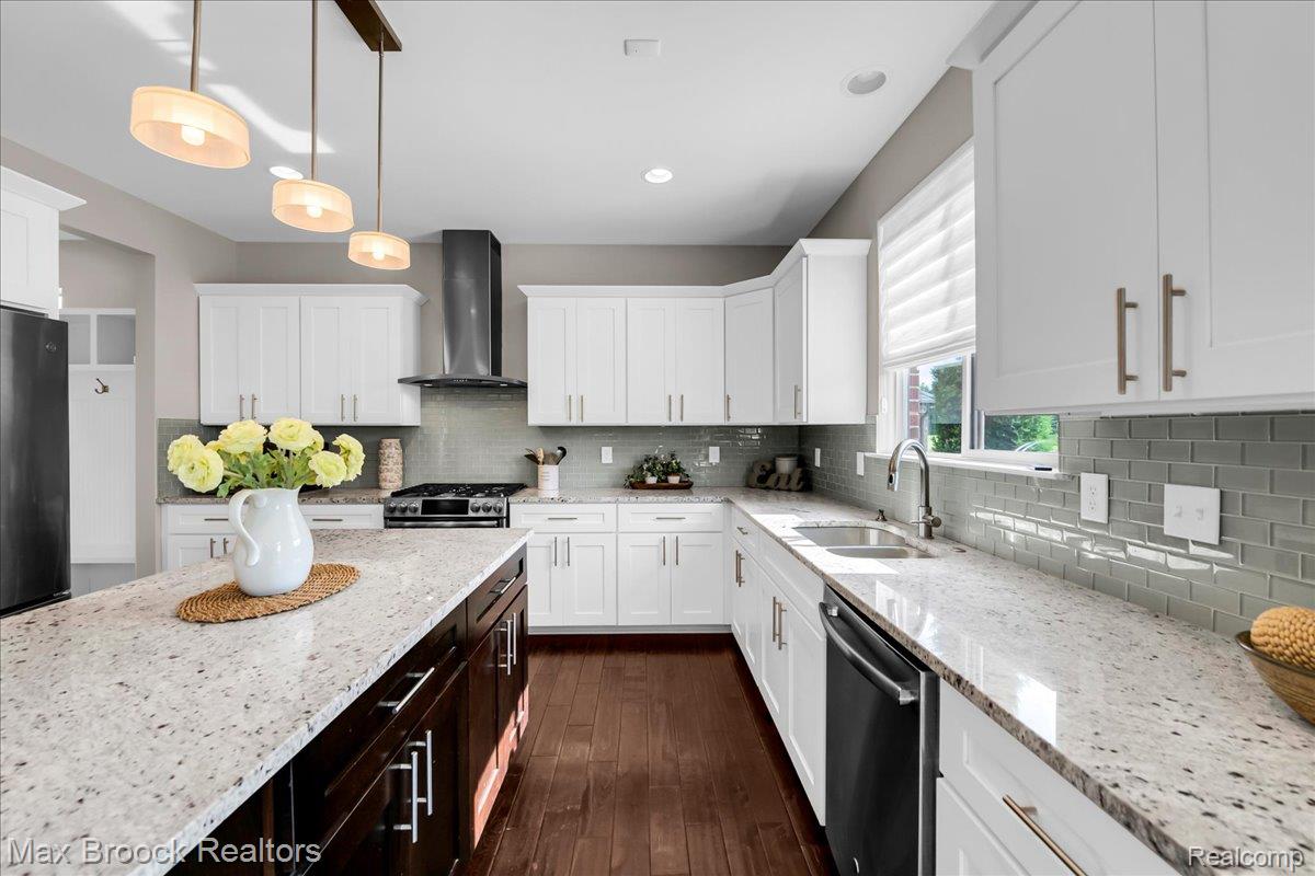 1126 Queensboro Drive Rochester, MI 48307 - Photo 22 of 66 Kitchen featuring a central island with a speckled countertop, white cabinetry, a gray subway tile backsplash, stainless steel appliances, and wood-finish flooring
