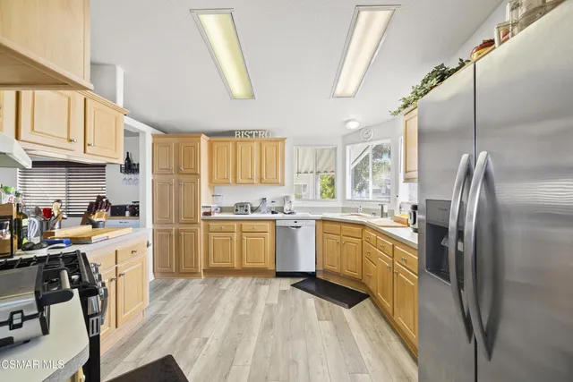 a kitchen with a refrigerator a sink dishwasher a stove and white cabinets with wooden floor