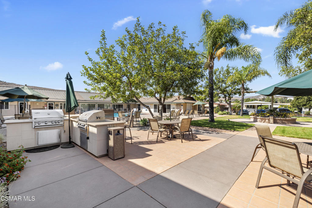 195 Tierra Rejada Road, Unit 52 Simi Valley, CA 93065 - Photo 29 of 34 a view of a patio with dining table and chairs under an umbrella