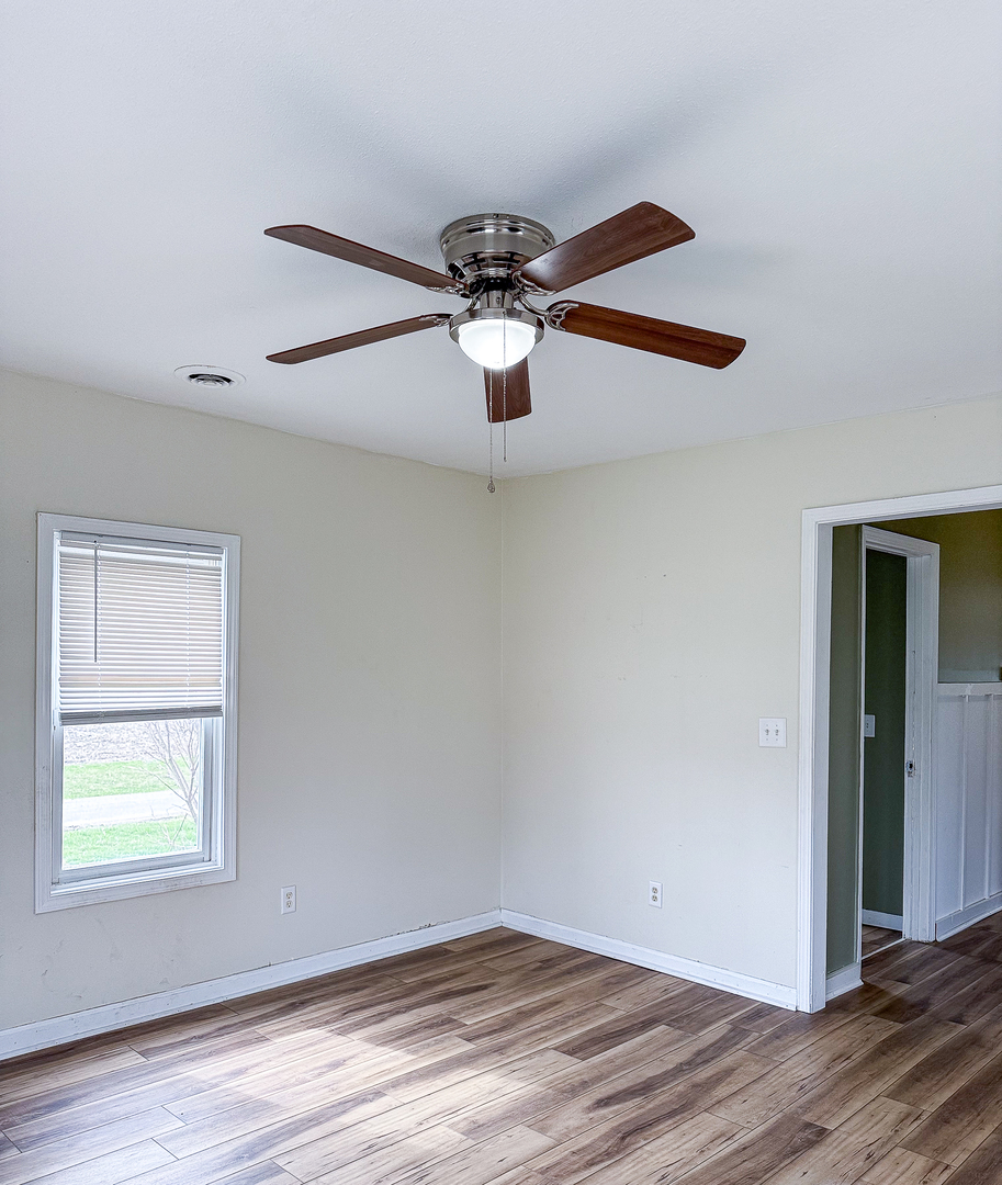 319 Missouri Street Atwood, IL 61913 - Photo 13 of 22 an empty room with wooden floor ceiling fan and window
