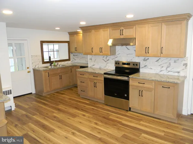 a kitchen with granite countertop a stove top oven sink and cabinets