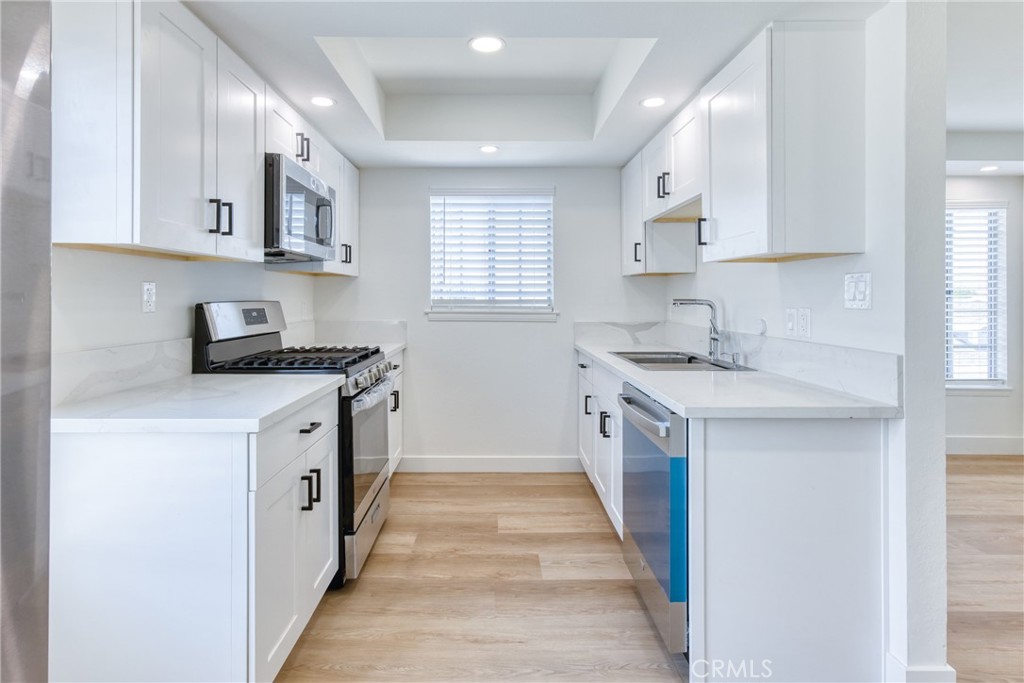 320 West Truslow Avenue, Unit D Fullerton, CA 92832 - Photo 19 of 25 a kitchen with white cabinets a sink stove and refrigerator
