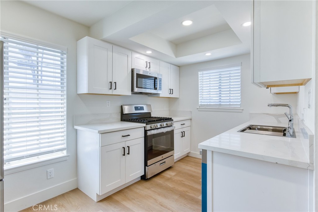 320 West Truslow Avenue, Unit D Fullerton, CA 92832 - Photo 20 of 25 a kitchen with stainless steel appliances granite countertop a sink dishwasher stove and white cabinets with wooden floor