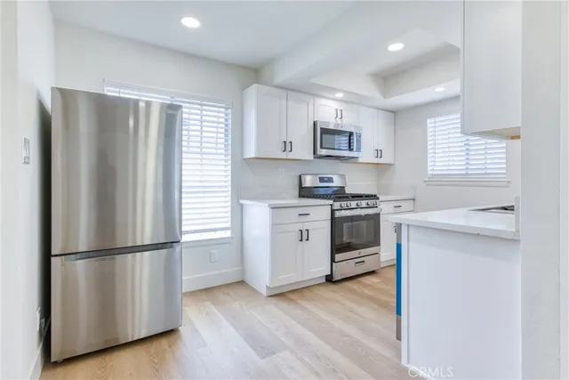 a view of a kitchen with a sink refrigerator and wooden floor