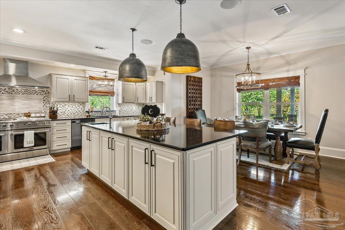 9050 Salter Road Pace, FL 32571 - Photo 8 of 48 a kitchen with stainless steel appliances granite countertop a stove a sink dishwasher a dining table chairs with white cabinets and wooden floor