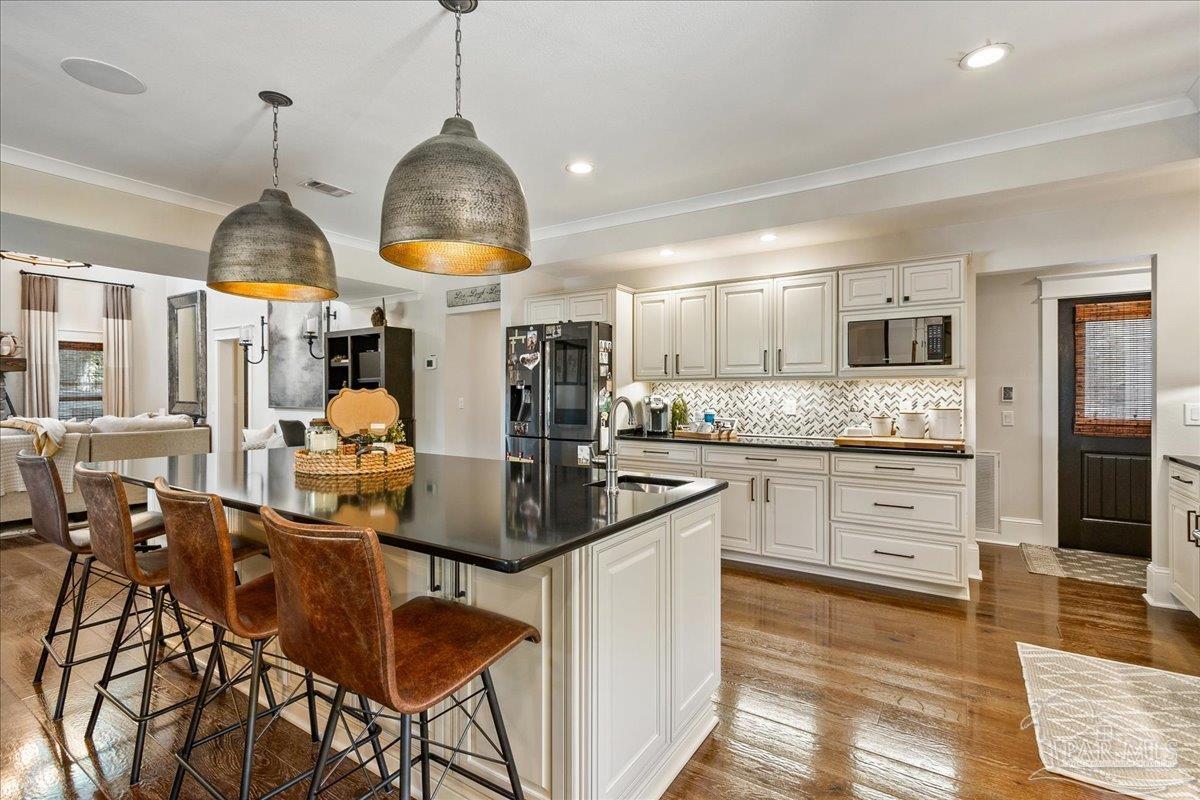 9050 Salter Road Pace, FL 32571 - Photo 9 of 48 a kitchen with stainless steel appliances kitchen island granite countertop a stove a refrigerator and a dining table with wooden floor