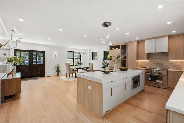 a kitchen with stainless steel appliances granite countertop a stove top oven a sink a refrigerator and white cabinets with wooden floor