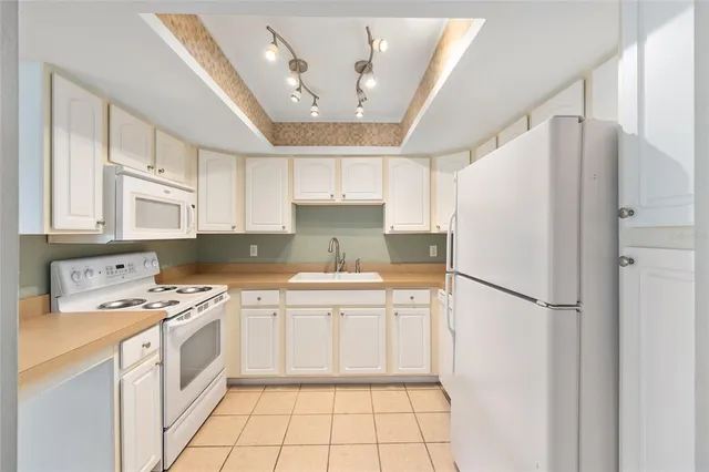 a kitchen with a white refrigerator a sink dishwasher a stove and white cabinets