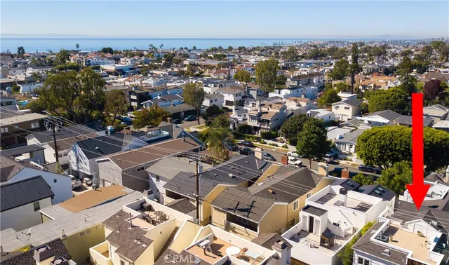 an aerial view of a city with lots of residential buildings and ocean view in back