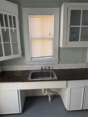 a bathroom with a granite countertop sink and a window