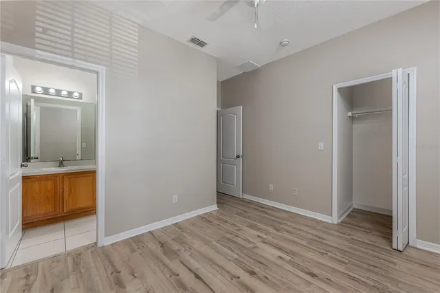 a view of an empty room with wooden floor and a bathroom