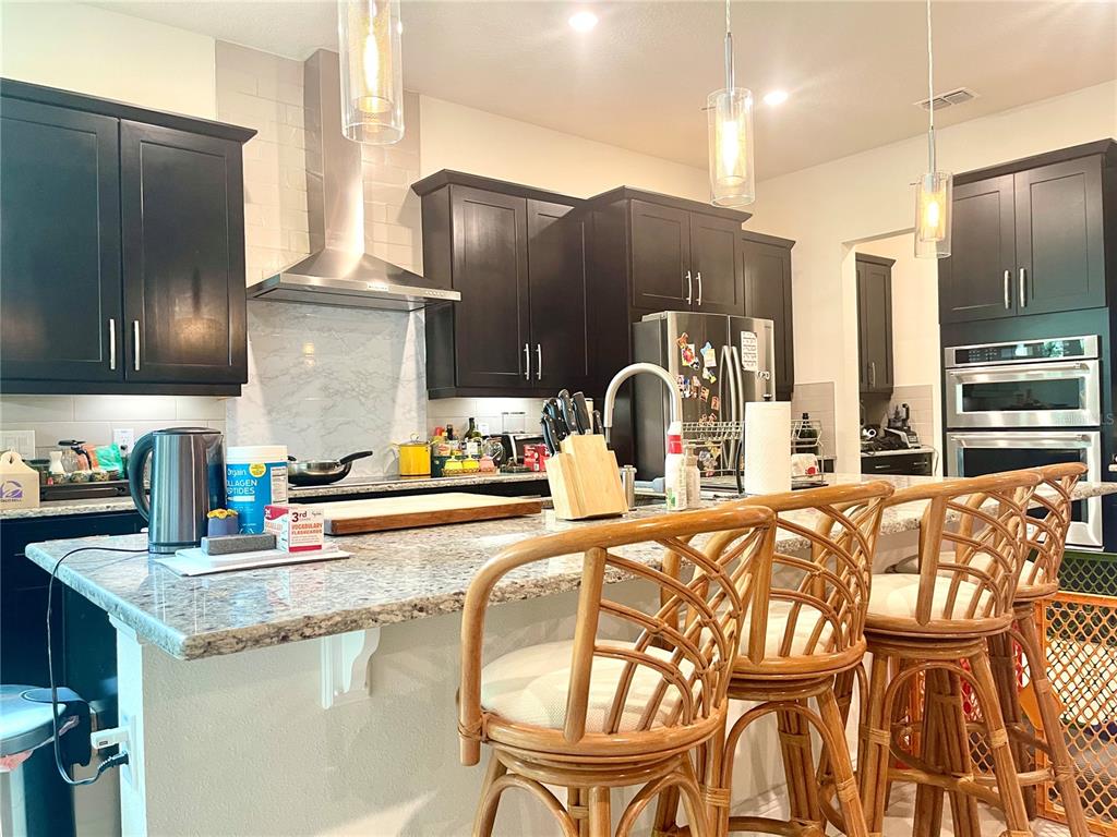 16611 Toccoa Row Winter Garden, FL 34787 - Photo 9 of 31 a kitchen with stainless steel appliances granite countertop a table chairs in it and wooden floors