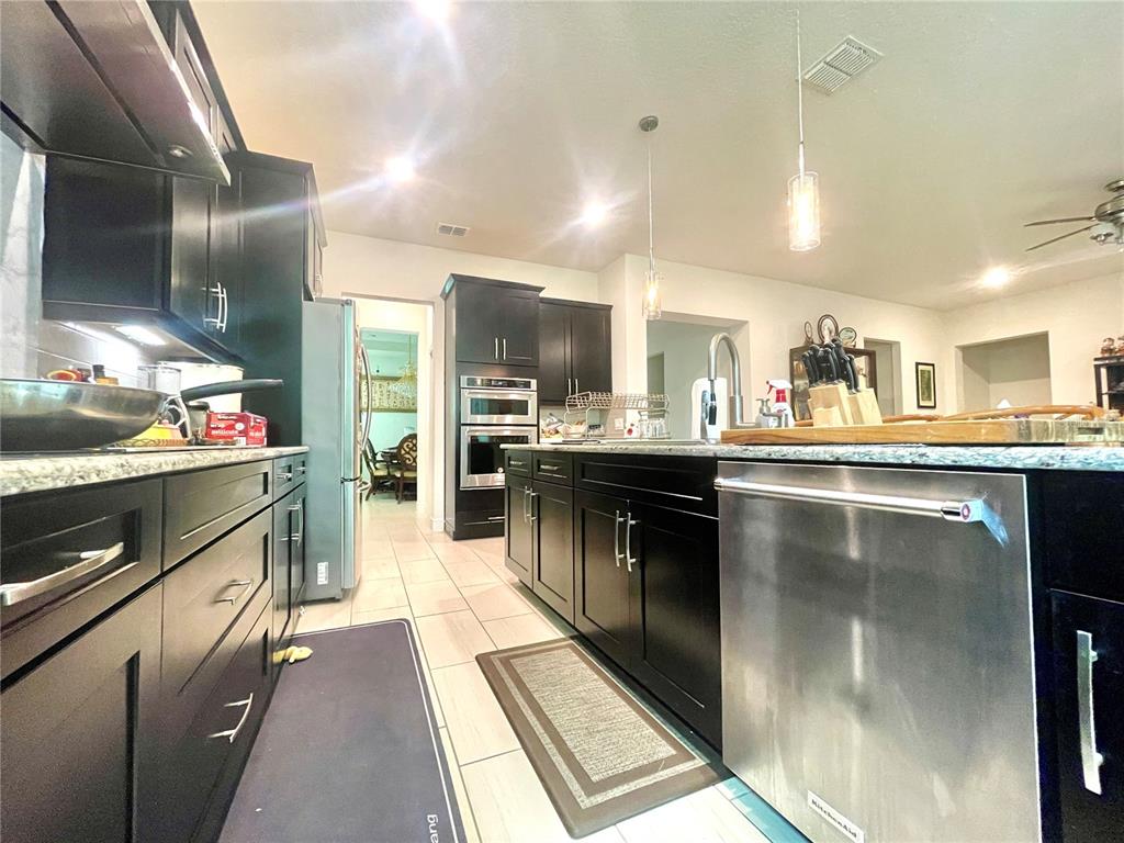 16611 Toccoa Row Winter Garden, FL 34787 - Photo 10 of 31 a kitchen with stainless steel appliances kitchen island granite countertop a stove a sink and a refrigerator