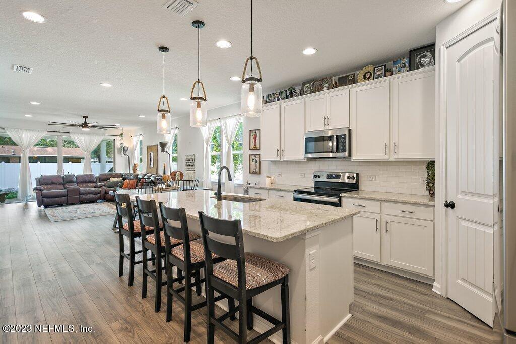 a kitchen with stainless steel appliances kitchen island granite countertop a stove a sink a microwave a island with a dining table and chairs