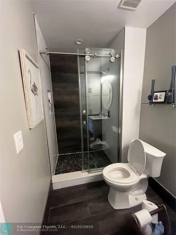 a white toilet sitting next to a bathroom sink and a shower