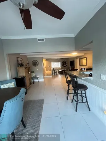 a living room with couches and a flat screen tv with kitchen view