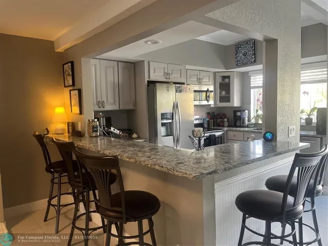a kitchen with stainless steel appliances granite countertop a dining table chairs and granite counter tops
