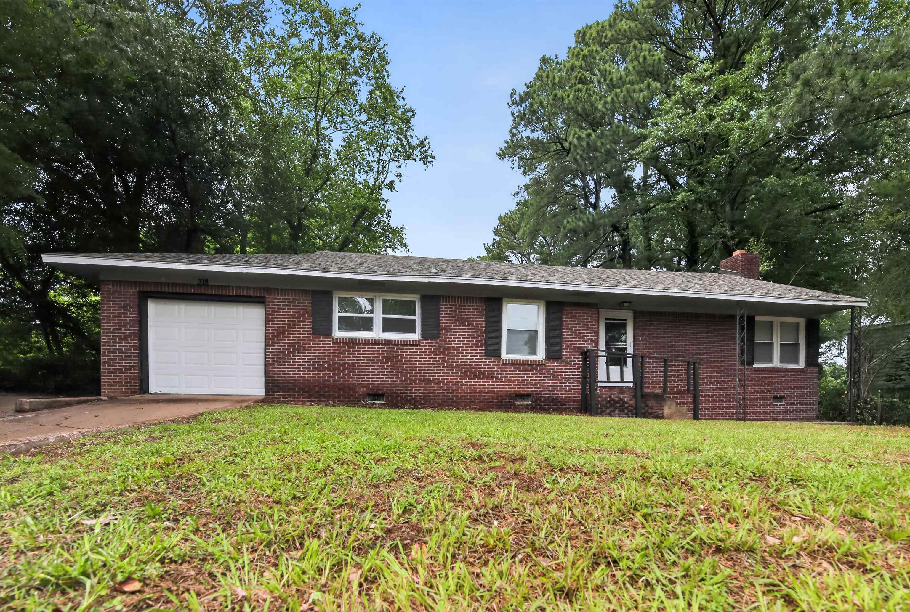 318 East Raines Road Memphis, TN 38109 - Photo 3 of 28 Brick exterior residence featuring a single-car garage with a white door, front porch with black railings, and multiple windows with dark shutters