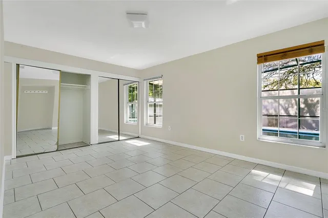 a view of an empty room with window and chandelier fan