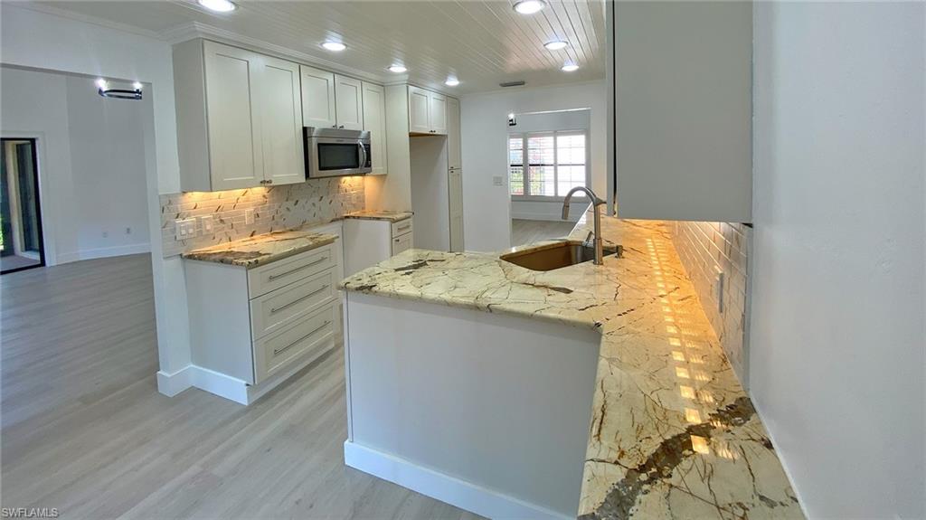 718 Reef Point Circle Naples, FL 34108 - Photo 11 of 23 a kitchen with granite countertop cabinets and wooden floor