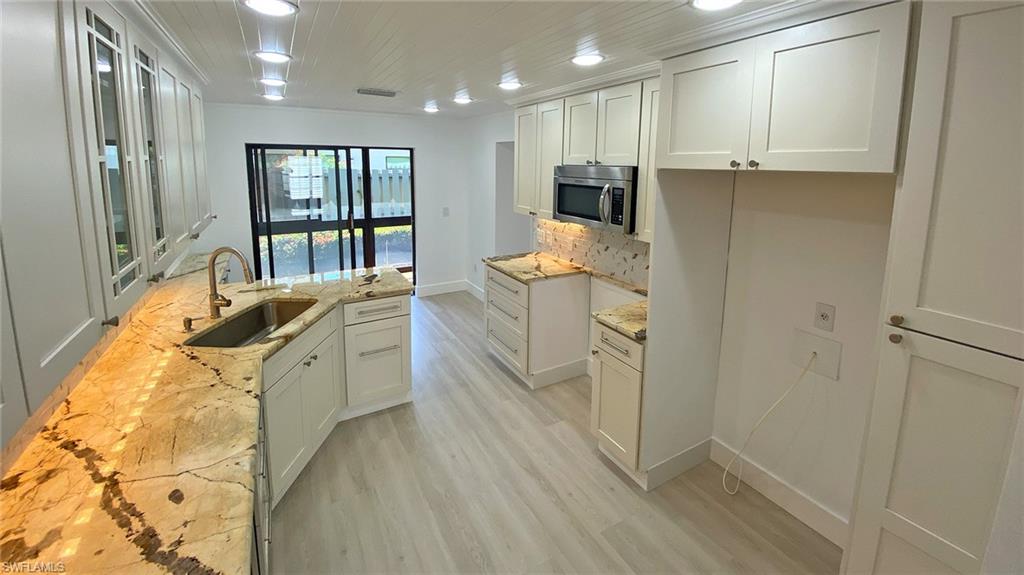 718 Reef Point Circle Naples, FL 34108 - Photo 12 of 23 a room with stainless steel appliances granite countertop a refrigerator a sink a stove and white cabinets with wooden floor