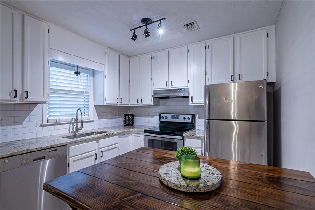 Newly renovated white kitchen with granite countertops, stainless steel appliances, and a custom wood top island!
