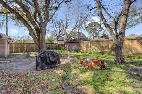 a backyard of a house with barbeque oven and a large tree