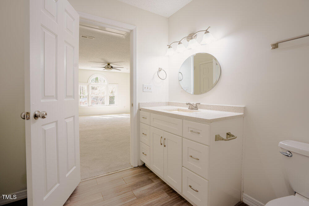 1514 Wiljohn Road Garner, NC 27529 - Photo 31 of 46 a bathroom with a toilet a sink a mirror and vanity
